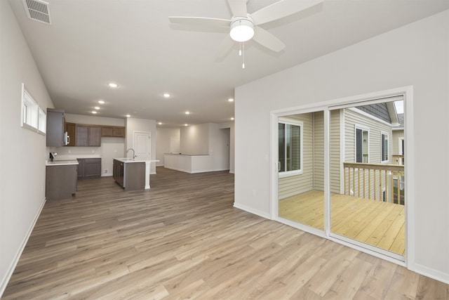 unfurnished living room with light wood-type flooring, ceiling fan, and sink