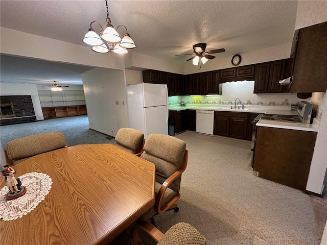 dining space with a textured ceiling, ceiling fan with notable chandelier, light colored carpet, and sink