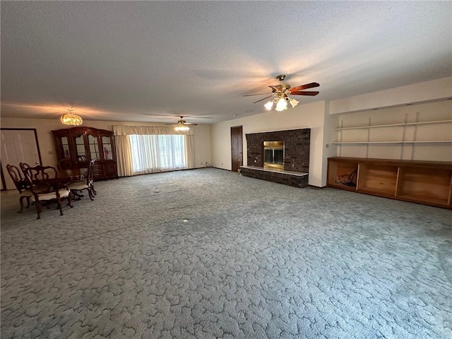 unfurnished living room featuring ceiling fan, a fireplace, carpet floors, and a textured ceiling