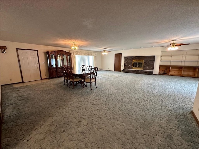 unfurnished dining area with ceiling fan with notable chandelier, a fireplace, carpet floors, and a textured ceiling