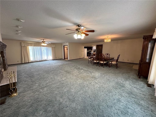 unfurnished living room with ceiling fan, a fireplace, carpet floors, and a textured ceiling