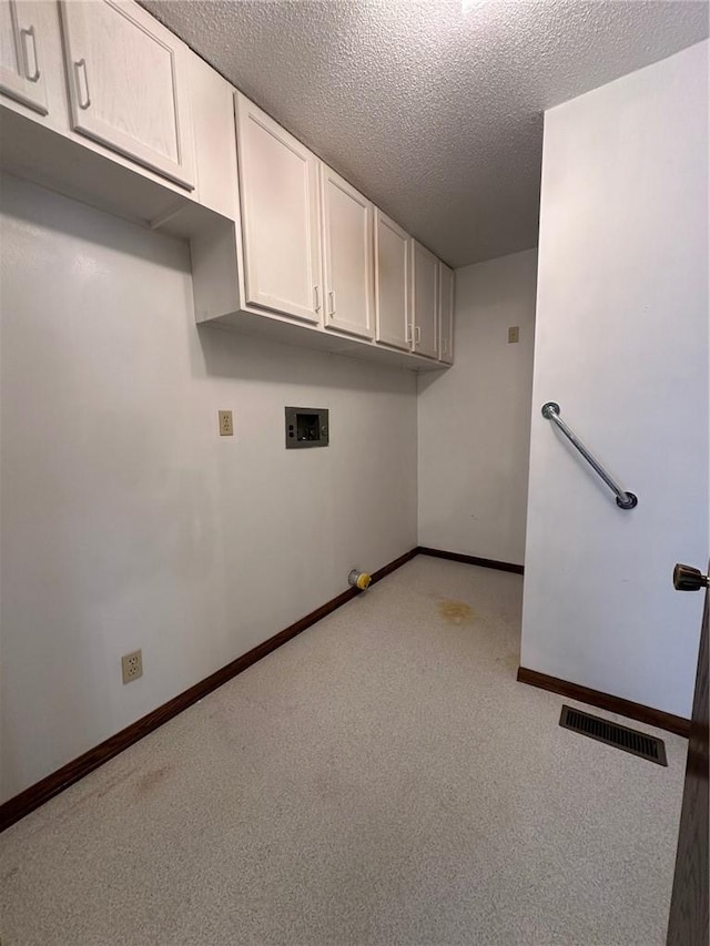 laundry area with cabinets, washer hookup, and a textured ceiling