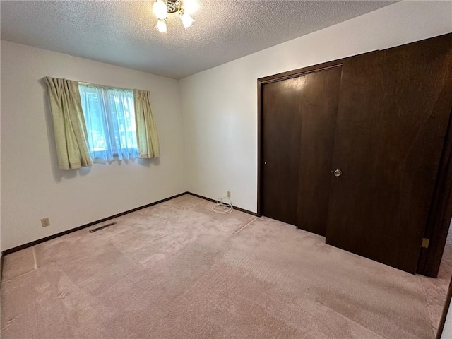 unfurnished bedroom with a textured ceiling, light colored carpet, and a closet