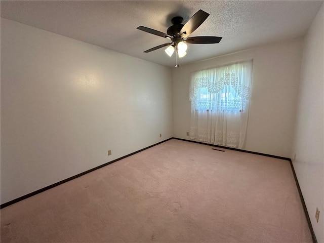 empty room featuring light carpet, ceiling fan, and a textured ceiling