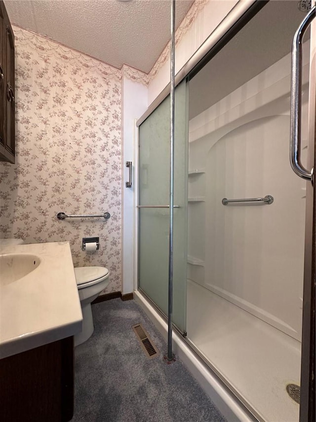 bathroom with a shower with door, vanity, a textured ceiling, and toilet