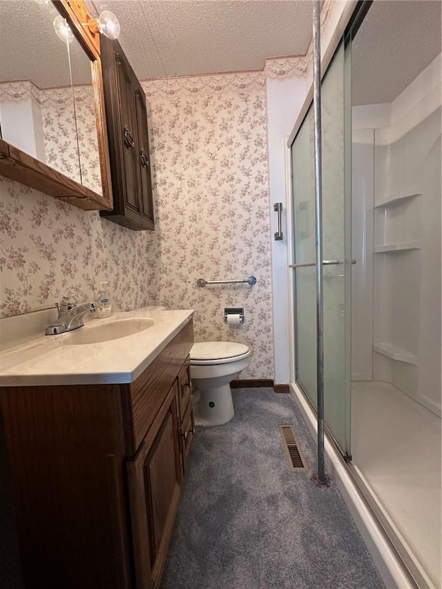 bathroom with a shower with door, vanity, a textured ceiling, and toilet