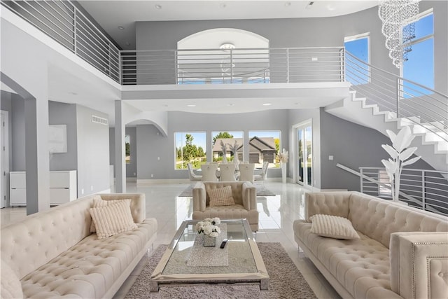 living room with a high ceiling, a notable chandelier, baseboards, and visible vents