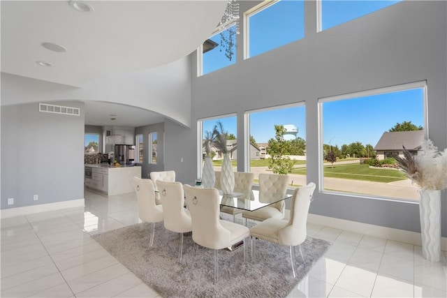 dining room with light tile patterned floors, visible vents, arched walkways, and baseboards