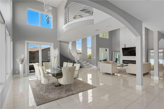 dining room featuring a wealth of natural light, baseboards, a towering ceiling, and a fireplace