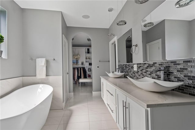 full bathroom featuring tile patterned floors, a freestanding tub, double vanity, and a sink