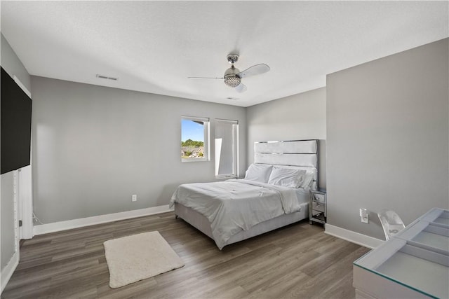 bedroom featuring visible vents, wood finished floors, baseboards, and ceiling fan