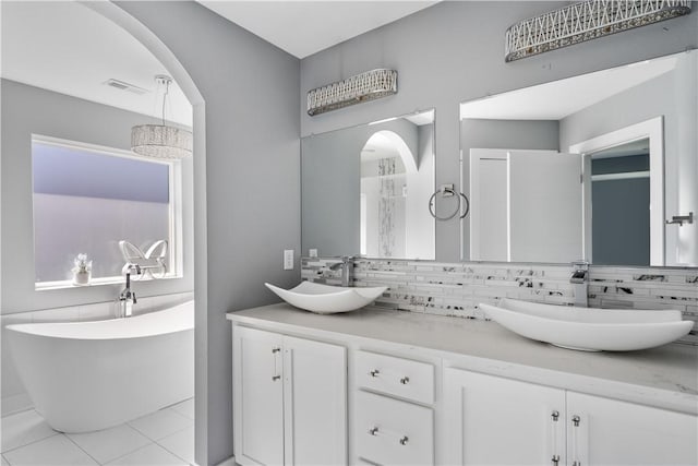 bathroom with a soaking tub, backsplash, visible vents, and a sink