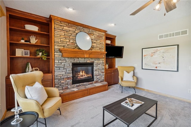 carpeted living room featuring a fireplace, built in features, and ceiling fan