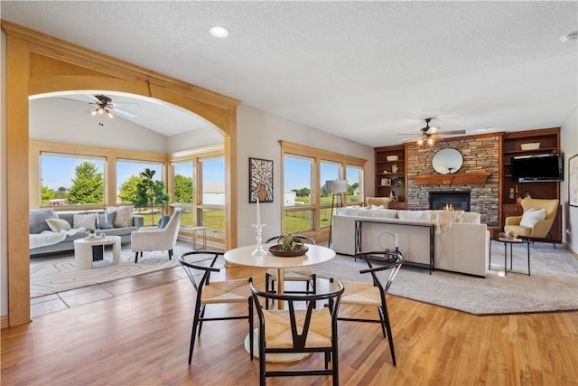 dining area with built in shelves, a fireplace, a textured ceiling, and ceiling fan