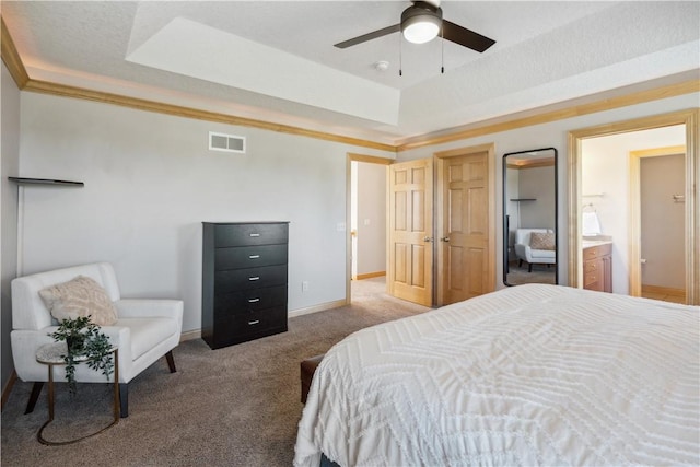 bedroom featuring a raised ceiling, crown molding, carpet flooring, ceiling fan, and connected bathroom