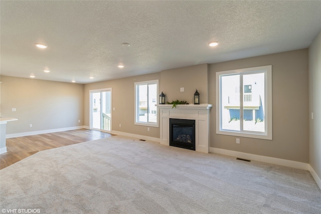 unfurnished living room with light wood-type flooring and a textured ceiling