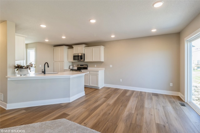 kitchen featuring stainless steel appliances, white cabinetry, light hardwood / wood-style floors, and sink