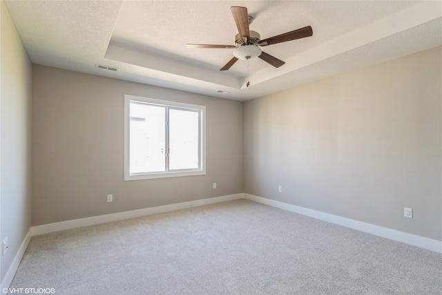 carpeted empty room with a tray ceiling and ceiling fan