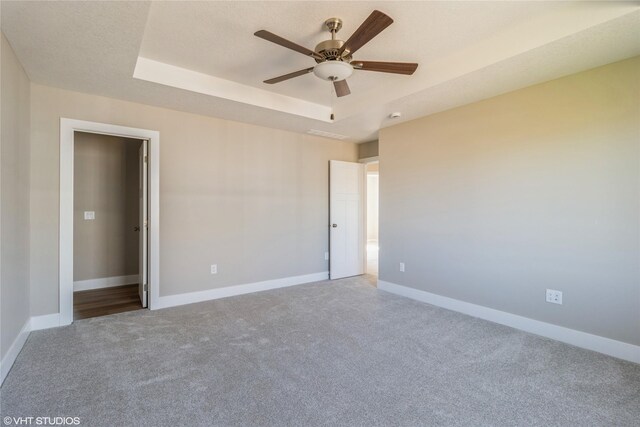 carpeted empty room featuring ceiling fan and a tray ceiling