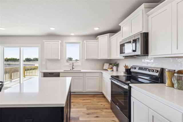 kitchen with white cabinets, sink, light wood-type flooring, and stainless steel appliances