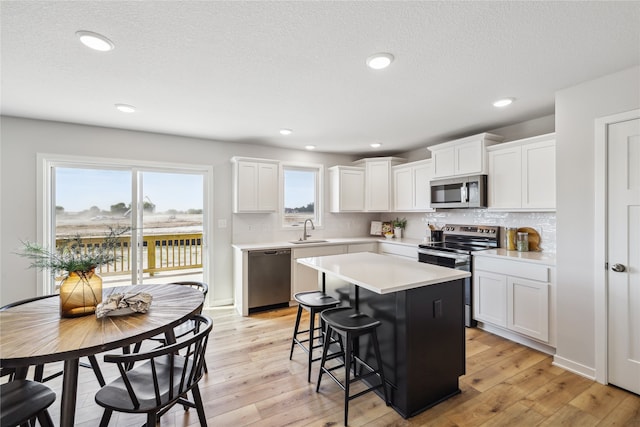 kitchen with white cabinets, a center island, stainless steel appliances, and sink