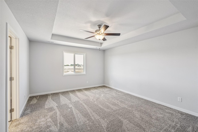 carpeted empty room with ceiling fan, a raised ceiling, and a textured ceiling