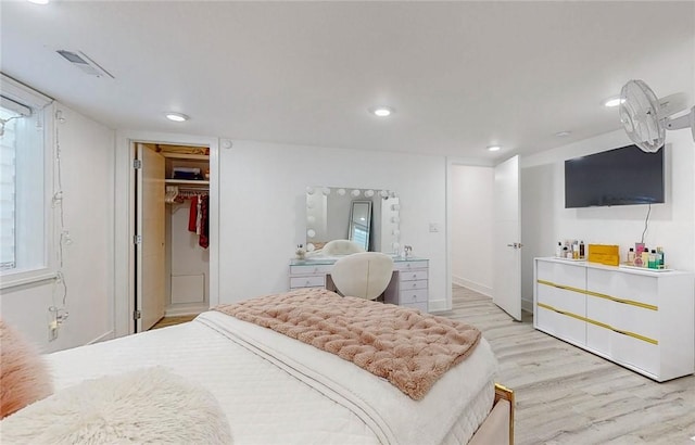 bedroom featuring light wood finished floors, a walk in closet, visible vents, and recessed lighting