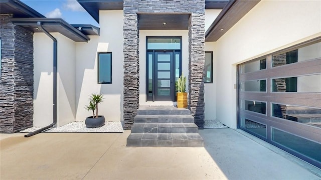 property entrance with a garage, stone siding, and stucco siding