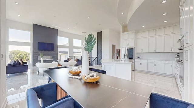 dining area featuring a high ceiling, a multi sided fireplace, and a wealth of natural light