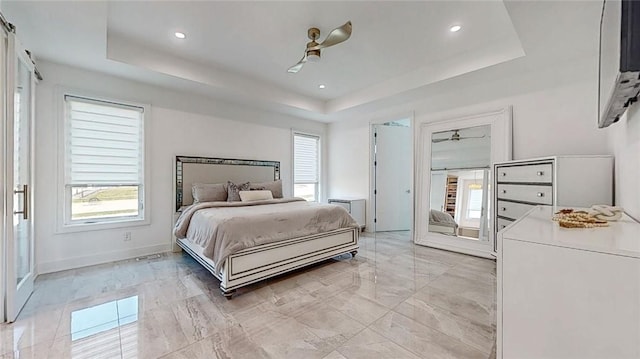 bedroom with a tray ceiling, recessed lighting, a ceiling fan, and baseboards