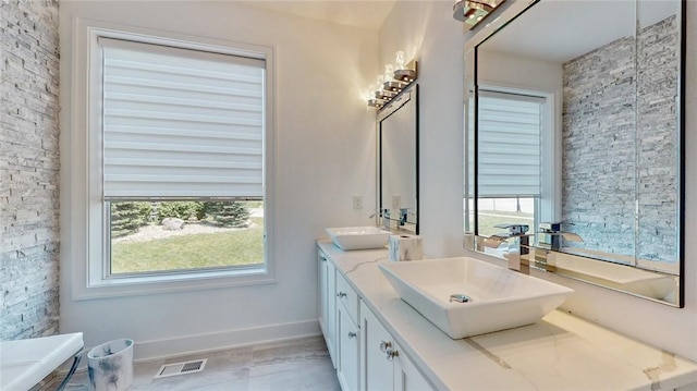 bathroom featuring double vanity, baseboards, visible vents, and a sink