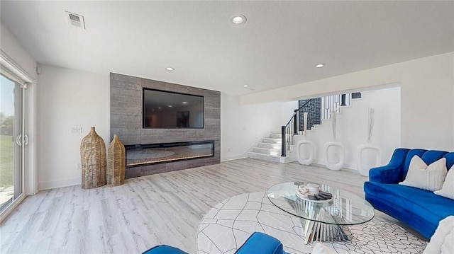 living area with stairway, a fireplace, wood finished floors, and a healthy amount of sunlight