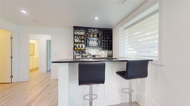 bar with recessed lighting, indoor wet bar, light wood-style flooring, and decorative backsplash