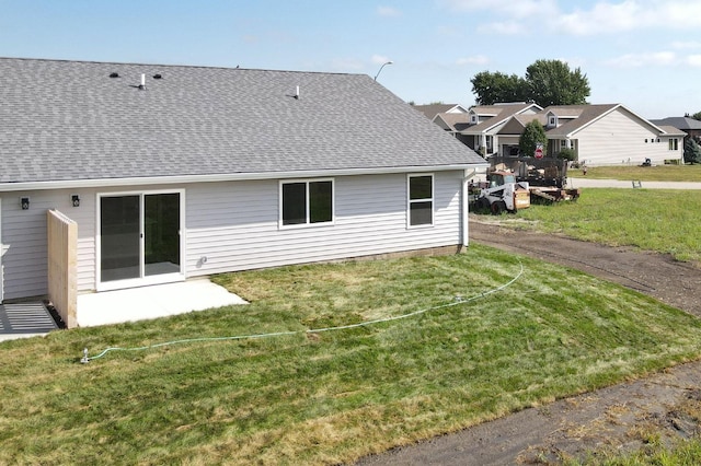 rear view of property with a patio area, a shingled roof, and a yard