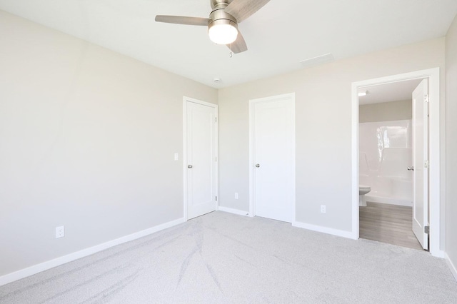 unfurnished bedroom with light carpet, ceiling fan, baseboards, and ensuite bathroom