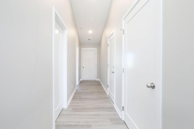 hallway featuring light wood-style flooring and baseboards