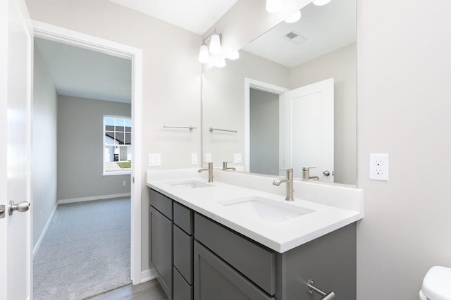 full bathroom with double vanity, baseboards, visible vents, and a sink