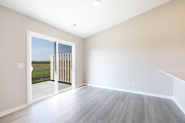 spare room featuring light wood-type flooring, visible vents, and baseboards