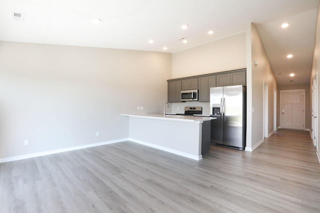 kitchen with open floor plan, stainless steel appliances, light countertops, and light wood-style flooring