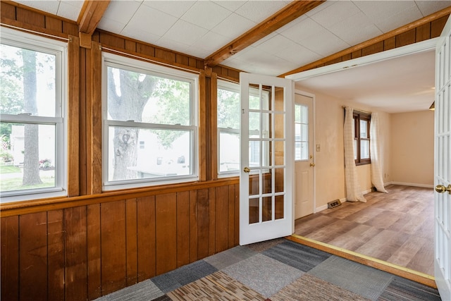 entryway featuring wooden walls, light wood-type flooring, and plenty of natural light