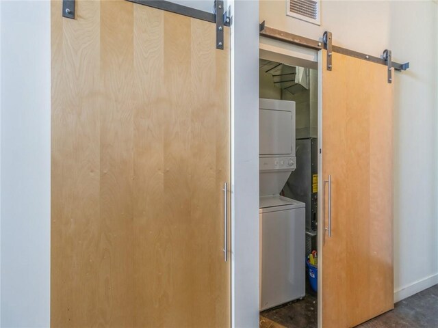 laundry room featuring stacked washer and clothes dryer and a barn door