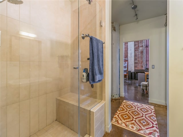 bathroom featuring tiled shower and rail lighting