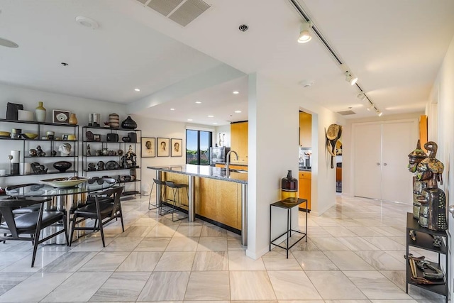 kitchen featuring a kitchen bar, sink, and rail lighting