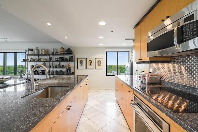 kitchen featuring a healthy amount of sunlight, dark stone countertops, sink, and appliances with stainless steel finishes