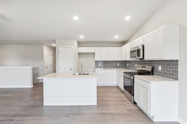 kitchen featuring sink, appliances with stainless steel finishes, a center island with sink, white cabinets, and light wood-type flooring