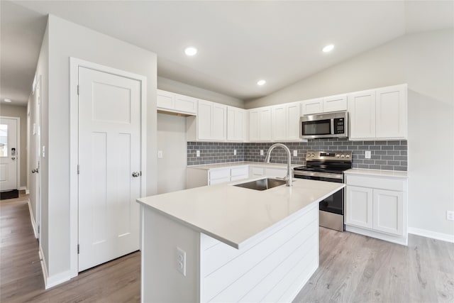 kitchen featuring stainless steel appliances, sink, light hardwood / wood-style floors, white cabinetry, and an island with sink