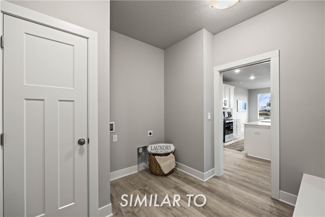 interior space with hookup for a washing machine, light wood-type flooring, a textured ceiling, and electric dryer hookup