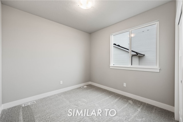 empty room with carpet flooring and a textured ceiling