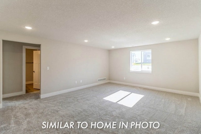 carpeted spare room featuring a textured ceiling