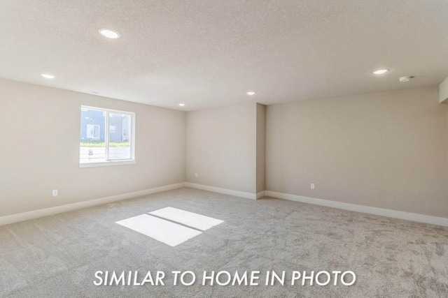 spare room featuring light colored carpet and a textured ceiling